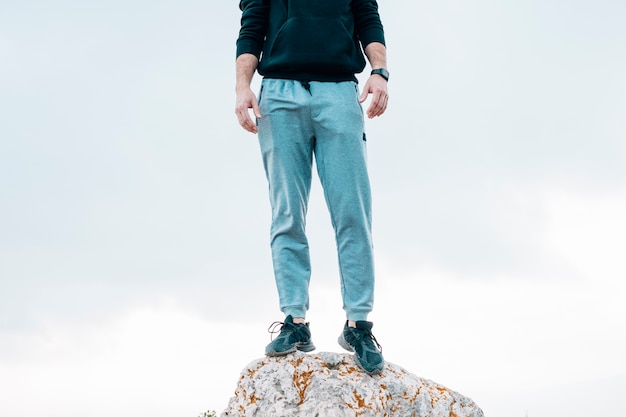 Person standing on a rock, wearing blue pants and black shoes.