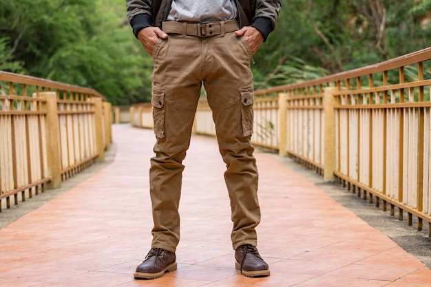 Person wearing cargo pants and boots, standing on a wooden bridge.
