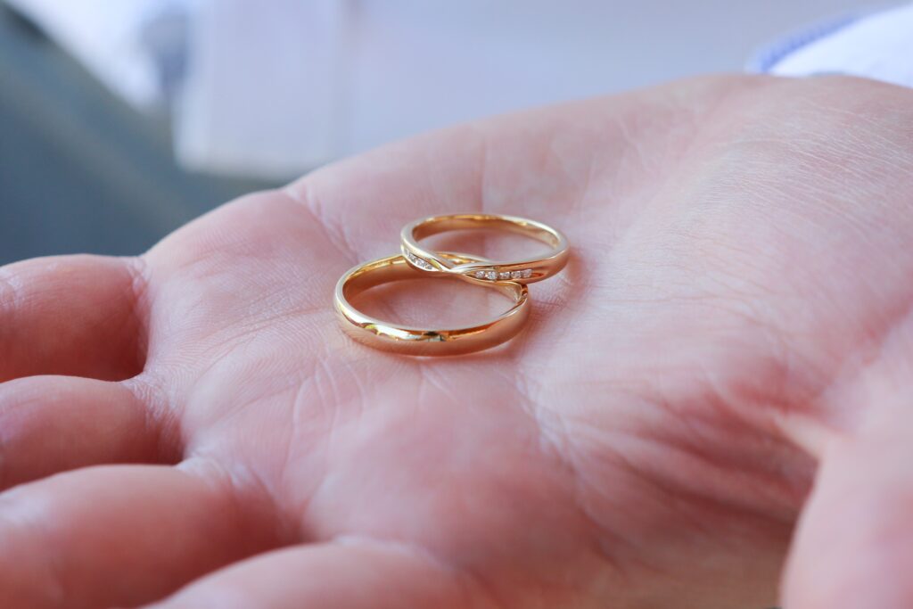 closeup shot person holding two gold wedding rings scaled